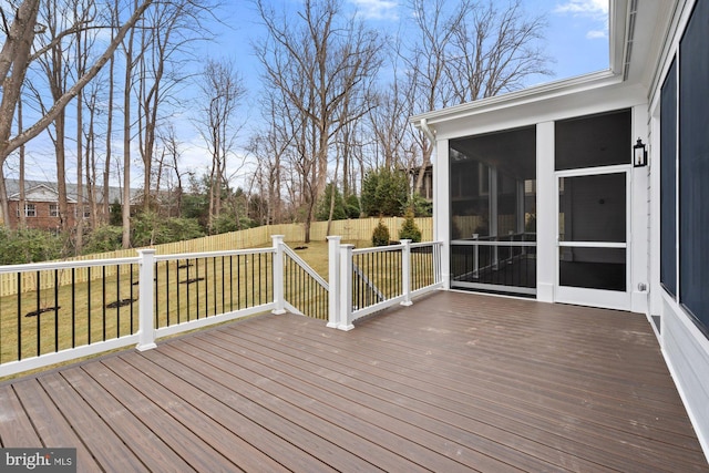 deck featuring a lawn, fence, and a sunroom