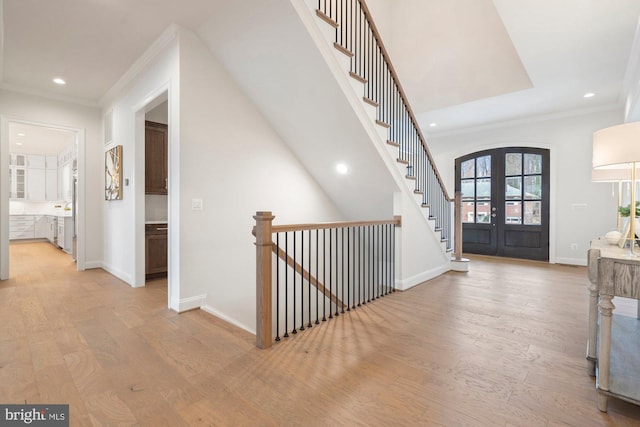 foyer entrance featuring french doors, baseboards, and light wood finished floors