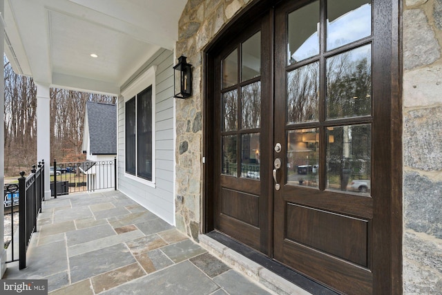 entrance to property with french doors, covered porch, and stone siding