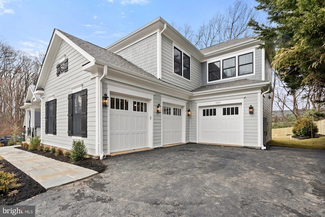 view of side of property with aphalt driveway and roof with shingles