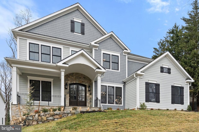 view of front of property with stone siding, french doors, and a front lawn