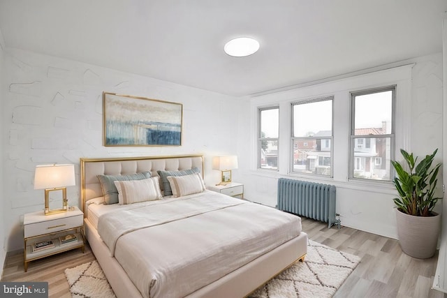 bedroom with radiator heating unit and light wood-style floors