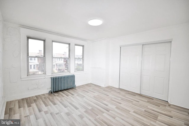 interior space featuring a closet, radiator, and light wood finished floors