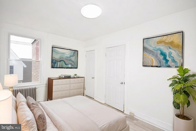 bedroom featuring radiator heating unit, wood finished floors, and baseboards