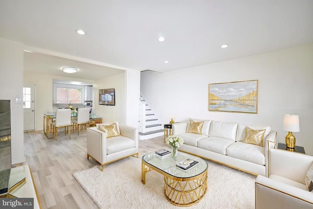 living room with recessed lighting, light wood-type flooring, and stairs