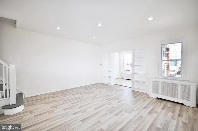 empty room with stairway, radiator, light wood-style floors, and recessed lighting