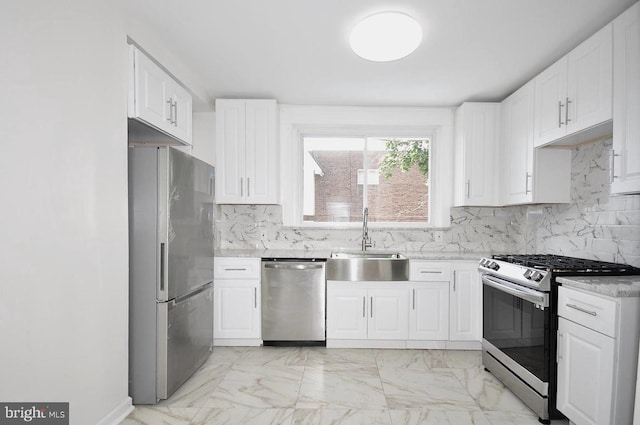 kitchen with marble finish floor, a sink, tasteful backsplash, white cabinetry, and appliances with stainless steel finishes