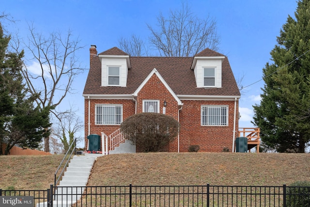 view of front of property with a fenced front yard, brick siding, a chimney, and a shingled roof