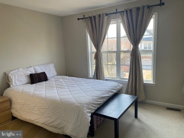 bedroom featuring baseboards, multiple windows, visible vents, and carpet flooring