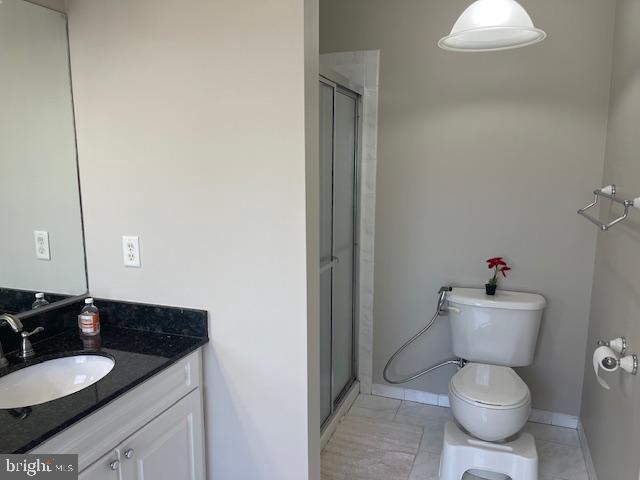 bathroom featuring vanity, a shower stall, toilet, and baseboards