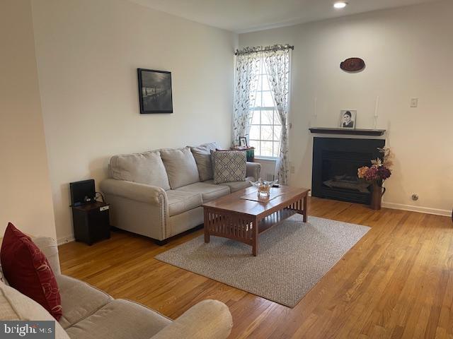 living area featuring recessed lighting, a fireplace, baseboards, and wood finished floors