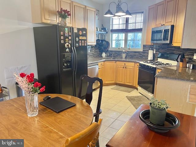 kitchen with light brown cabinetry, decorative light fixtures, light tile patterned floors, decorative backsplash, and stainless steel appliances