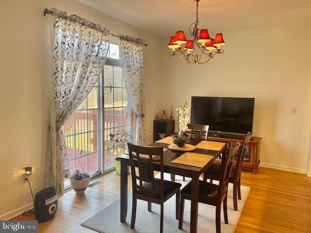 dining area featuring a chandelier, visible vents, baseboards, and wood finished floors