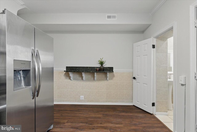 kitchen with wood finished floors, dark stone countertops, visible vents, and stainless steel refrigerator with ice dispenser