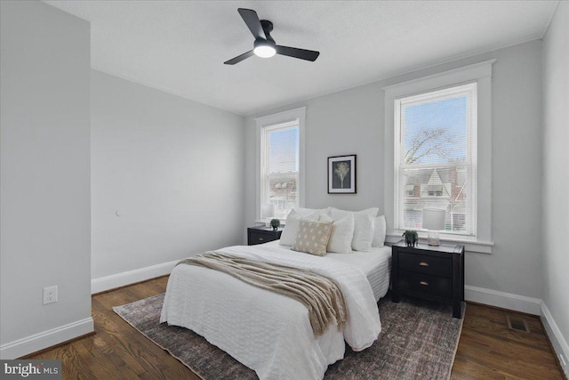 bedroom featuring ceiling fan, visible vents, baseboards, and wood finished floors