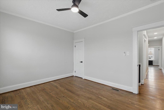 empty room featuring a ceiling fan, wood finished floors, visible vents, and baseboards