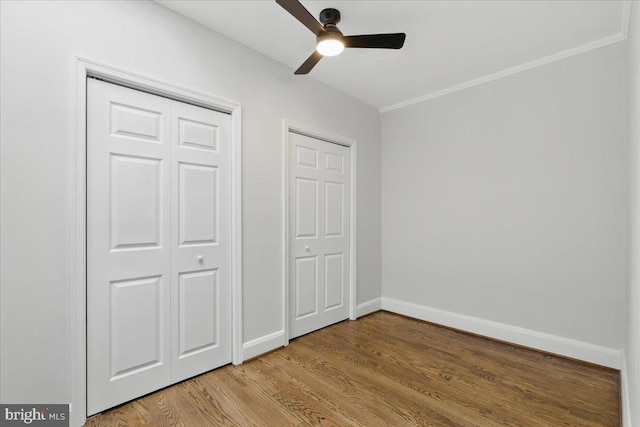 unfurnished bedroom with ornamental molding, a ceiling fan, baseboards, and wood finished floors