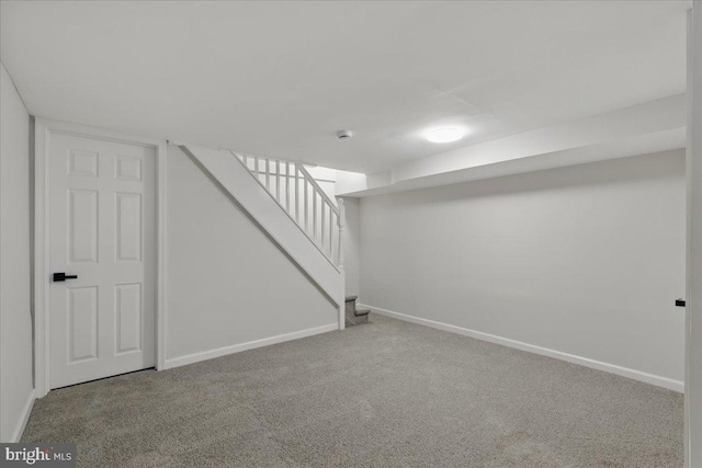 finished below grade area featuring stairway, baseboards, and carpet floors