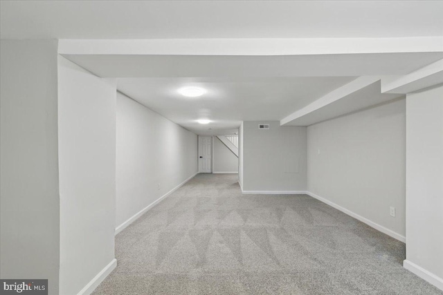 finished basement with baseboards, visible vents, and carpet floors