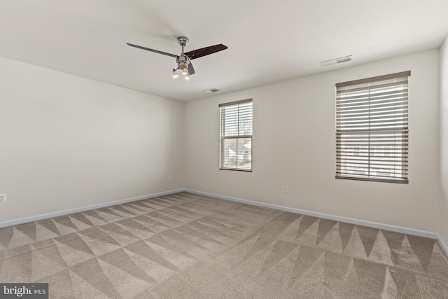 unfurnished room with visible vents, light carpet, baseboards, and a ceiling fan