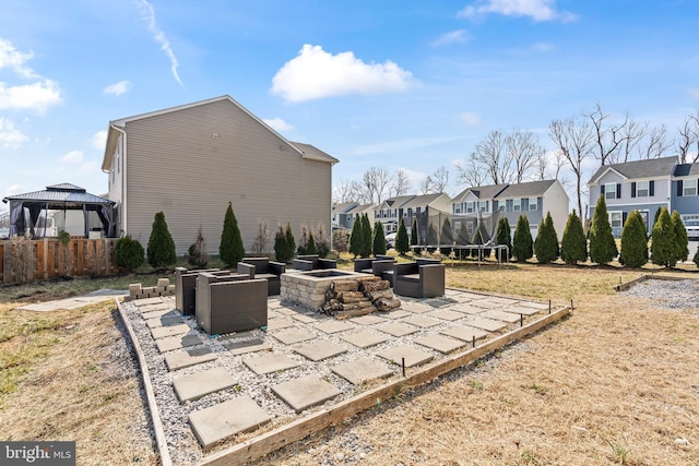 view of patio with a trampoline, fence, a residential view, an outdoor fire pit, and a gazebo