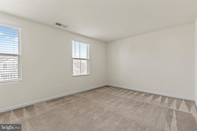 unfurnished room featuring visible vents, baseboards, and light colored carpet