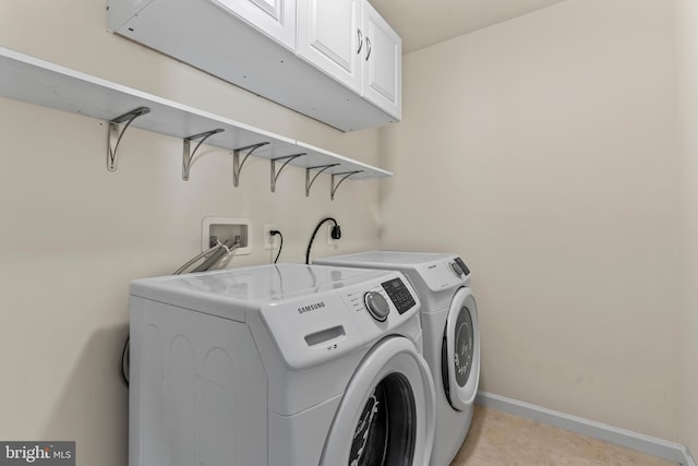 laundry area featuring washing machine and dryer, cabinet space, and baseboards