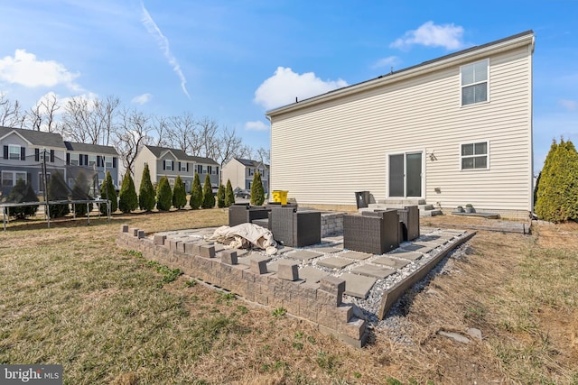 back of house featuring a patio, a trampoline, a yard, a residential view, and an outdoor hangout area