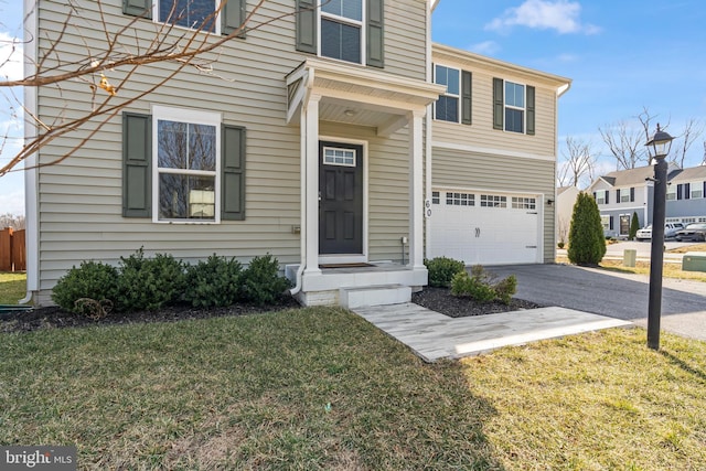 entrance to property with aphalt driveway, a garage, and a yard