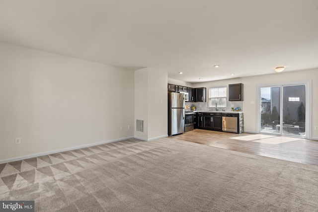 unfurnished living room with recessed lighting, visible vents, light colored carpet, and baseboards