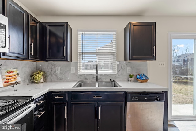 kitchen featuring light stone countertops, a sink, dishwasher, tasteful backsplash, and dark cabinets