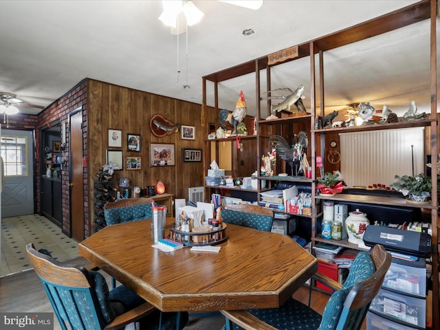 dining area featuring wooden walls and a ceiling fan