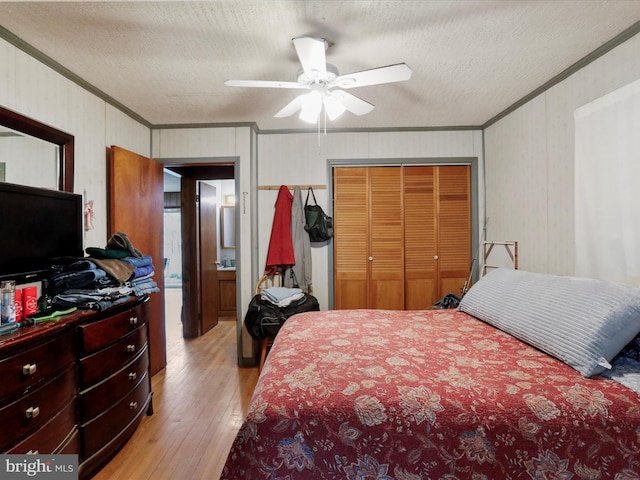 bedroom with a closet, a textured ceiling, light wood-style floors, and ornamental molding