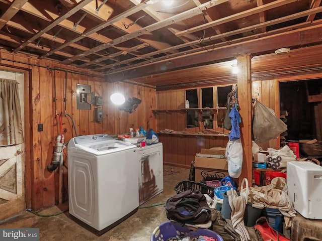 clothes washing area with wooden walls, independent washer and dryer, and laundry area