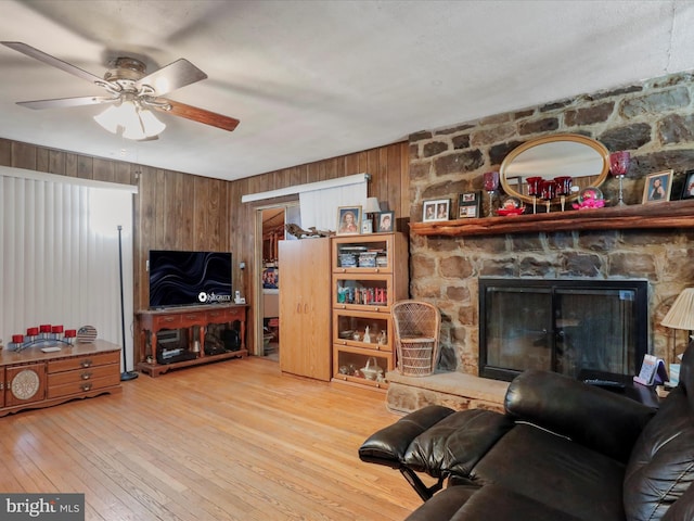 living room featuring wooden walls, a fireplace, wood-type flooring, and ceiling fan