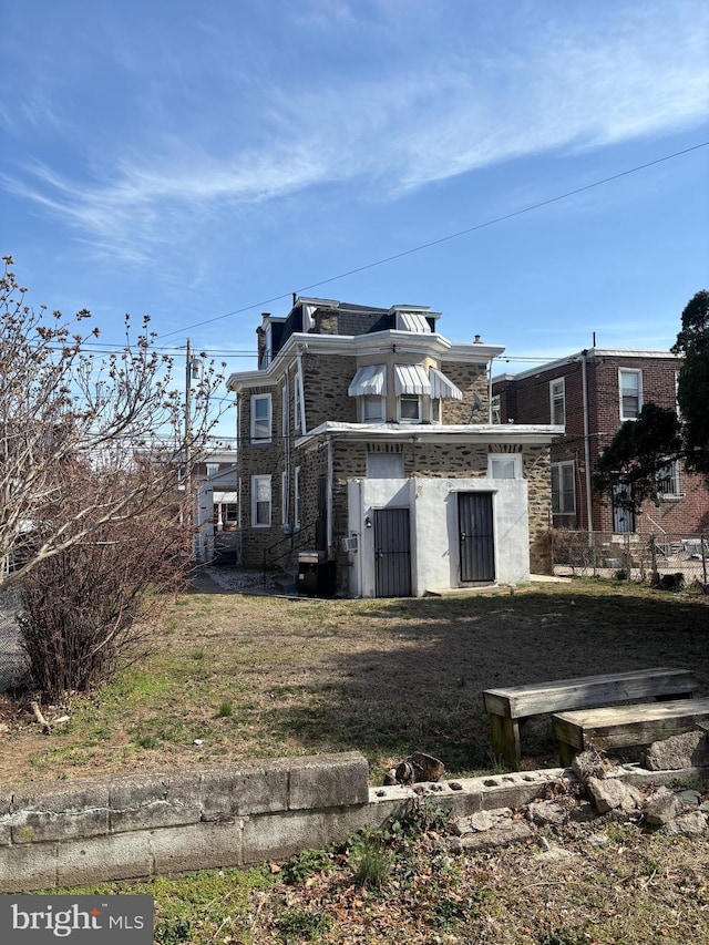 view of side of home featuring stone siding and mansard roof