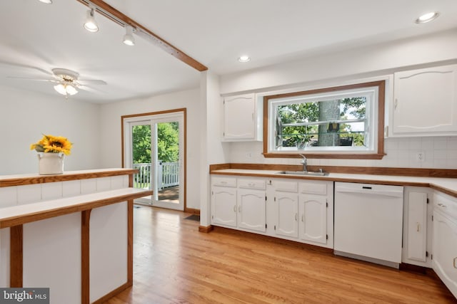 kitchen with a sink, tasteful backsplash, white cabinets, and white dishwasher