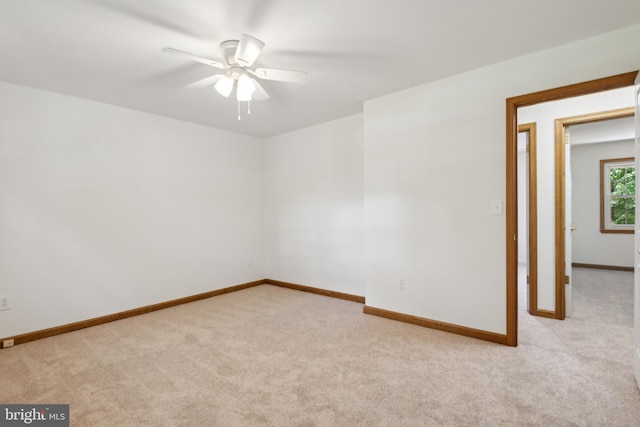 empty room featuring ceiling fan, baseboards, and light carpet