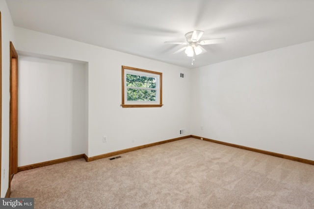 spare room with visible vents, carpet floors, baseboards, and a ceiling fan