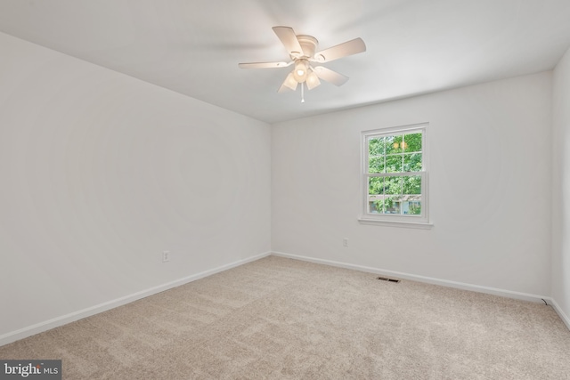 spare room with carpet flooring, visible vents, baseboards, and a ceiling fan