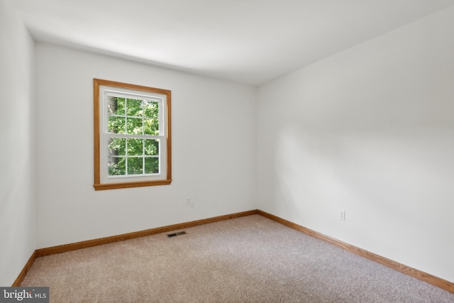 empty room with baseboards, visible vents, and carpet floors