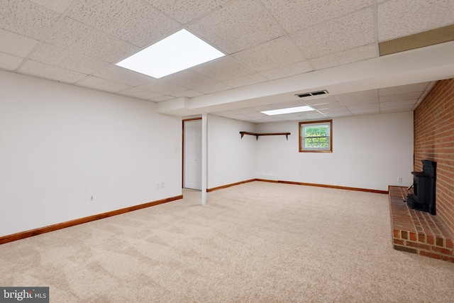 basement with carpet flooring, baseboards, visible vents, and a drop ceiling