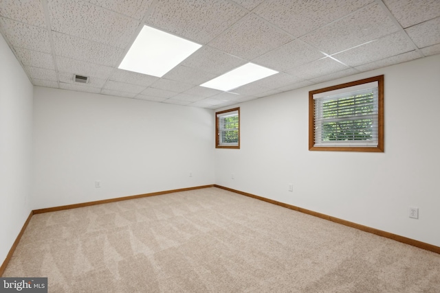 carpeted spare room featuring visible vents, a paneled ceiling, and baseboards