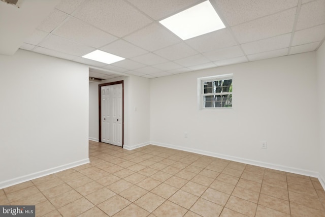 spare room featuring a paneled ceiling and baseboards