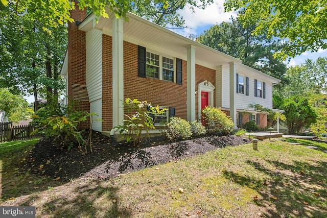 raised ranch featuring brick siding, a chimney, and fence