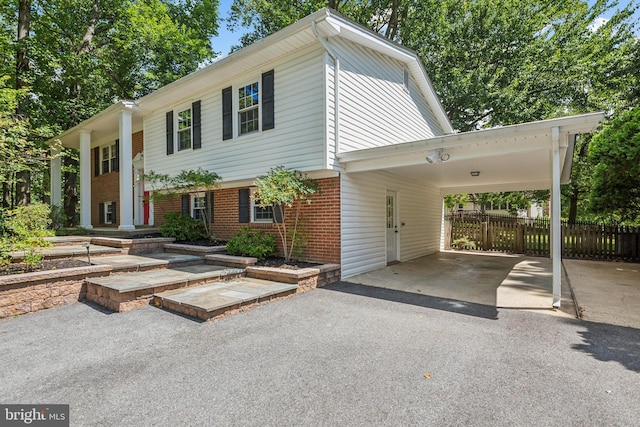 view of front of property with brick siding, an attached carport, driveway, and fence