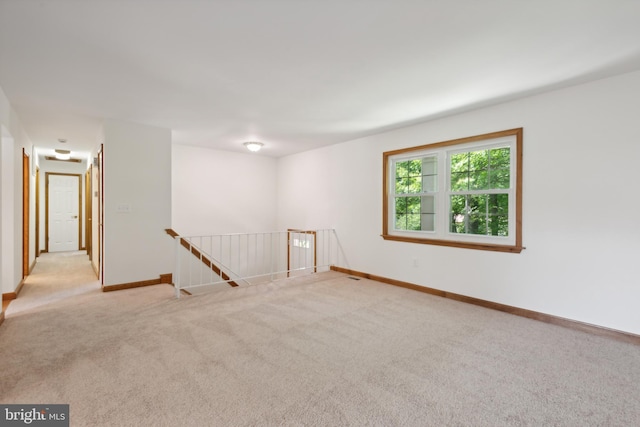 empty room featuring light carpet and baseboards