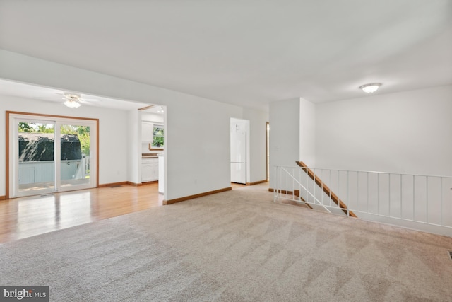 carpeted spare room with wood finished floors and baseboards