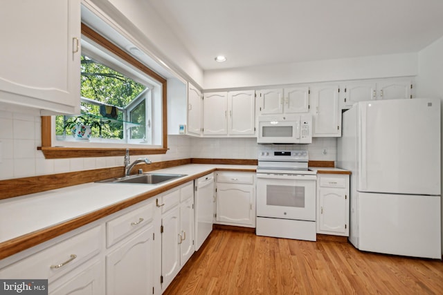 kitchen with white cabinetry, white appliances, and a sink