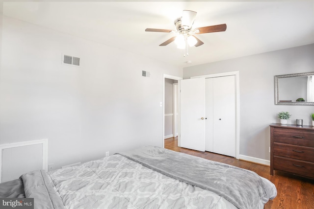 bedroom with a ceiling fan, wood finished floors, visible vents, and a closet